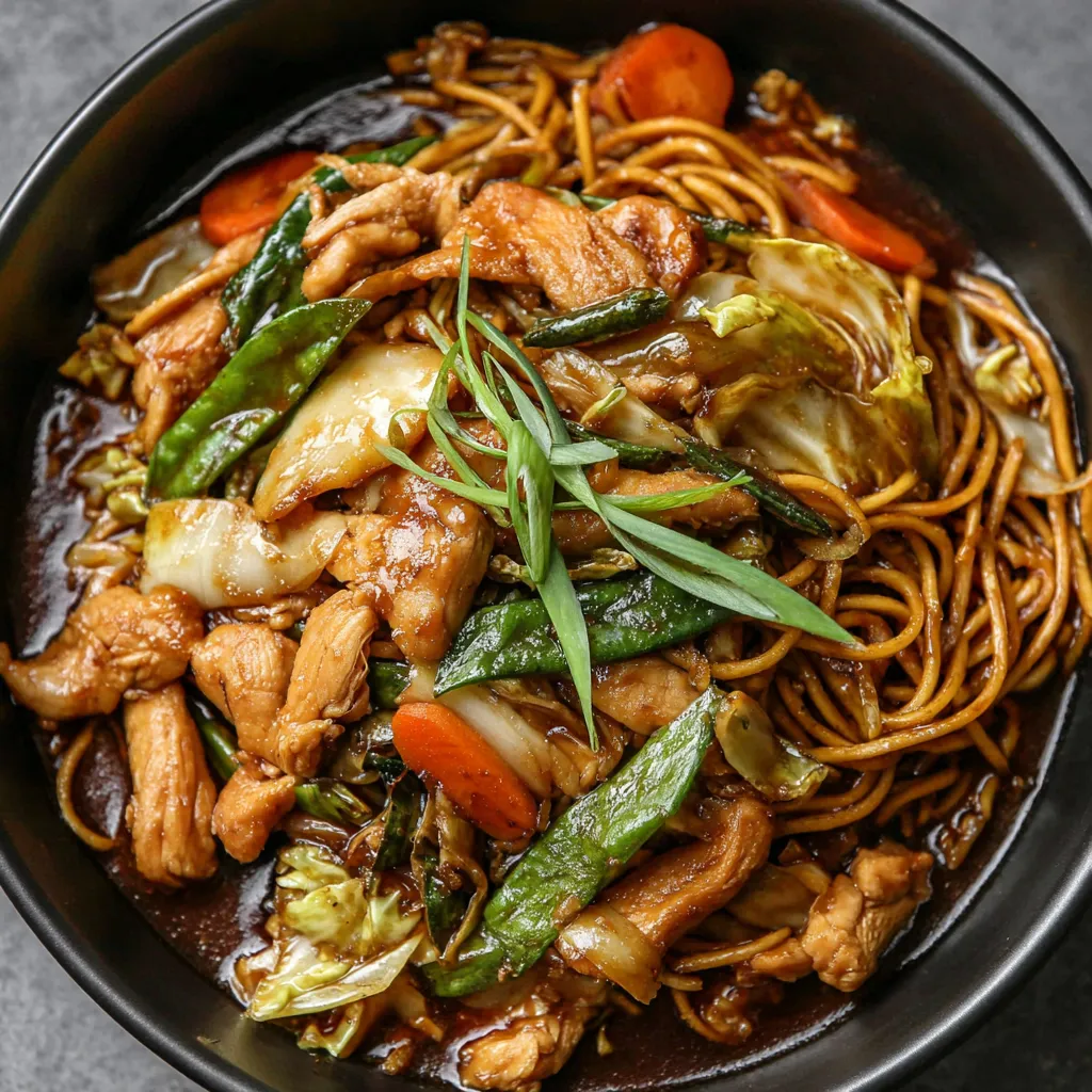 A bowl of chicken chow mein with vegetables.