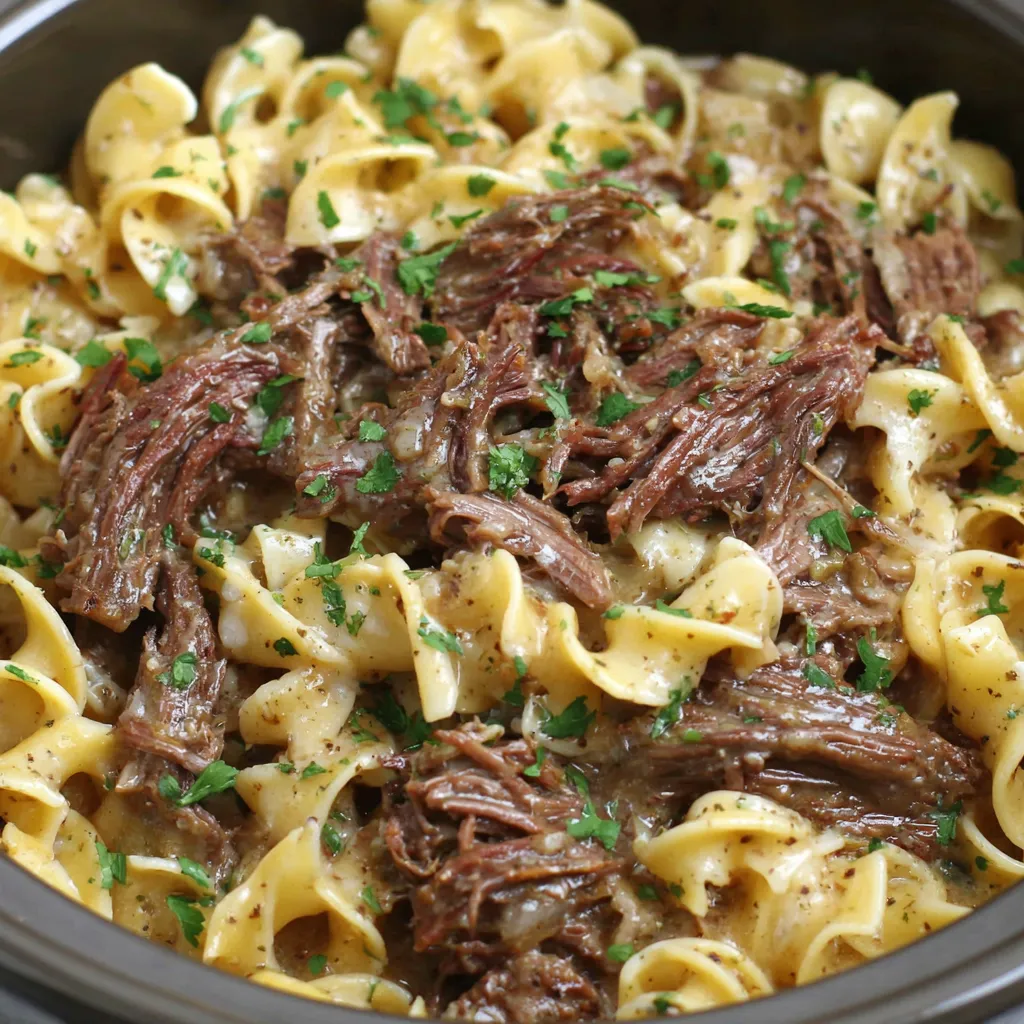 A close up of a crock pot filled with beef and noodles.