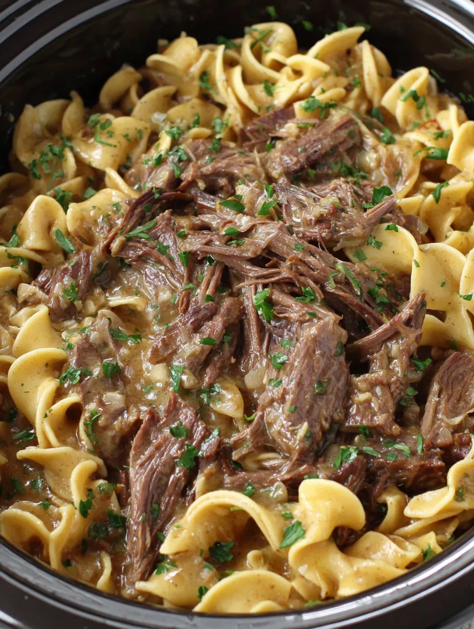 A close up of a crock pot filled with beef and noodles.
