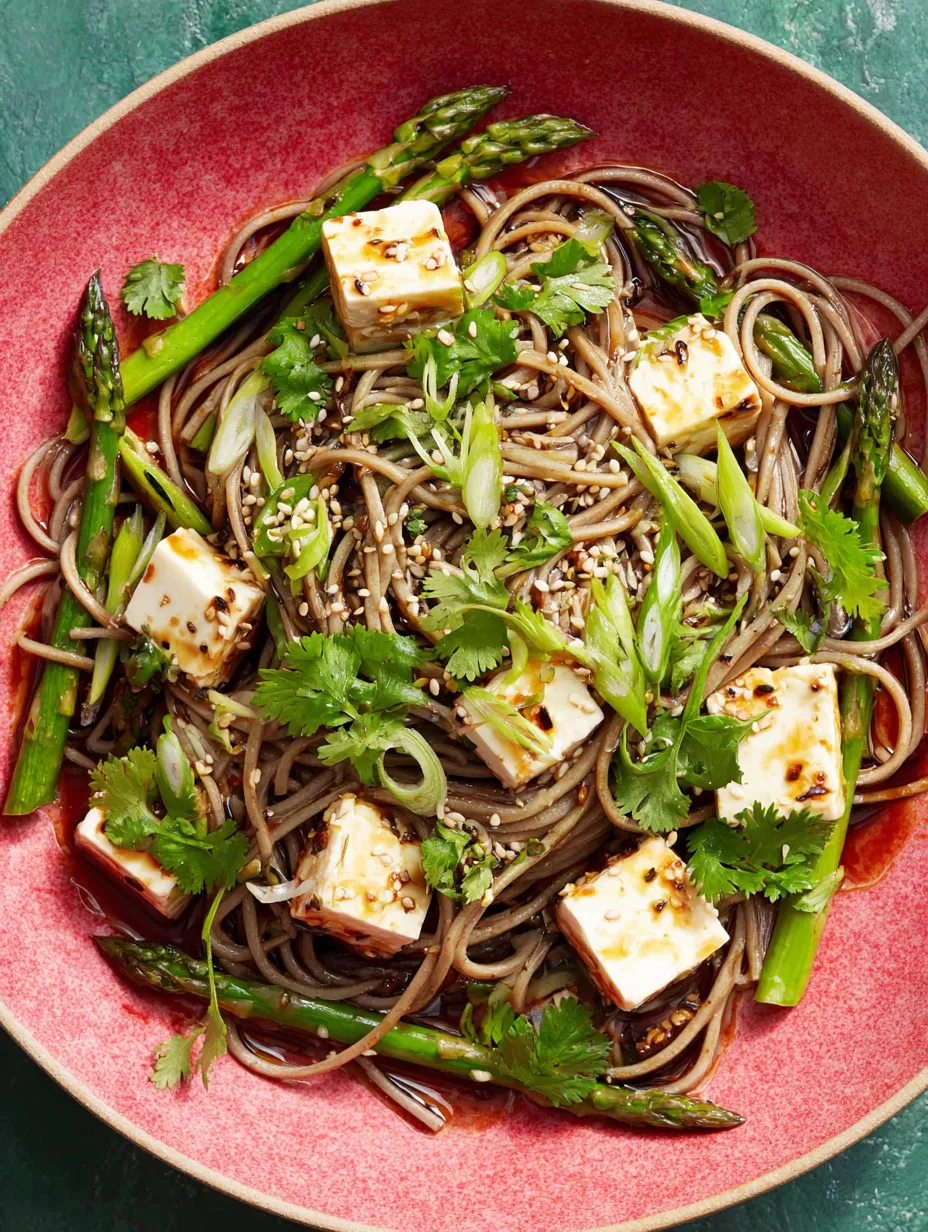 A bowl of noodles with tofu and vegetables.